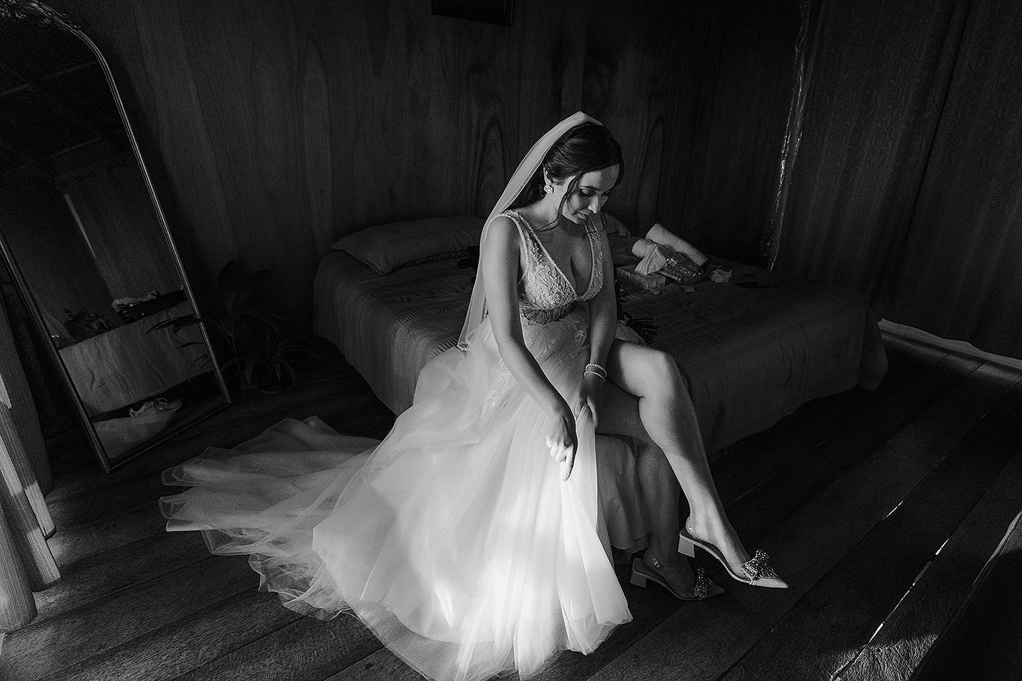 Eli sentada en la cama luciendo su vestido en su boda en Mazatlán, México.