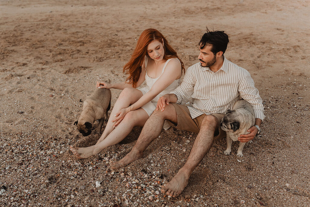 Sesión de pareja en Mazatlán de Xiomara y Alejandro junto al mar sentados con sus mascotas